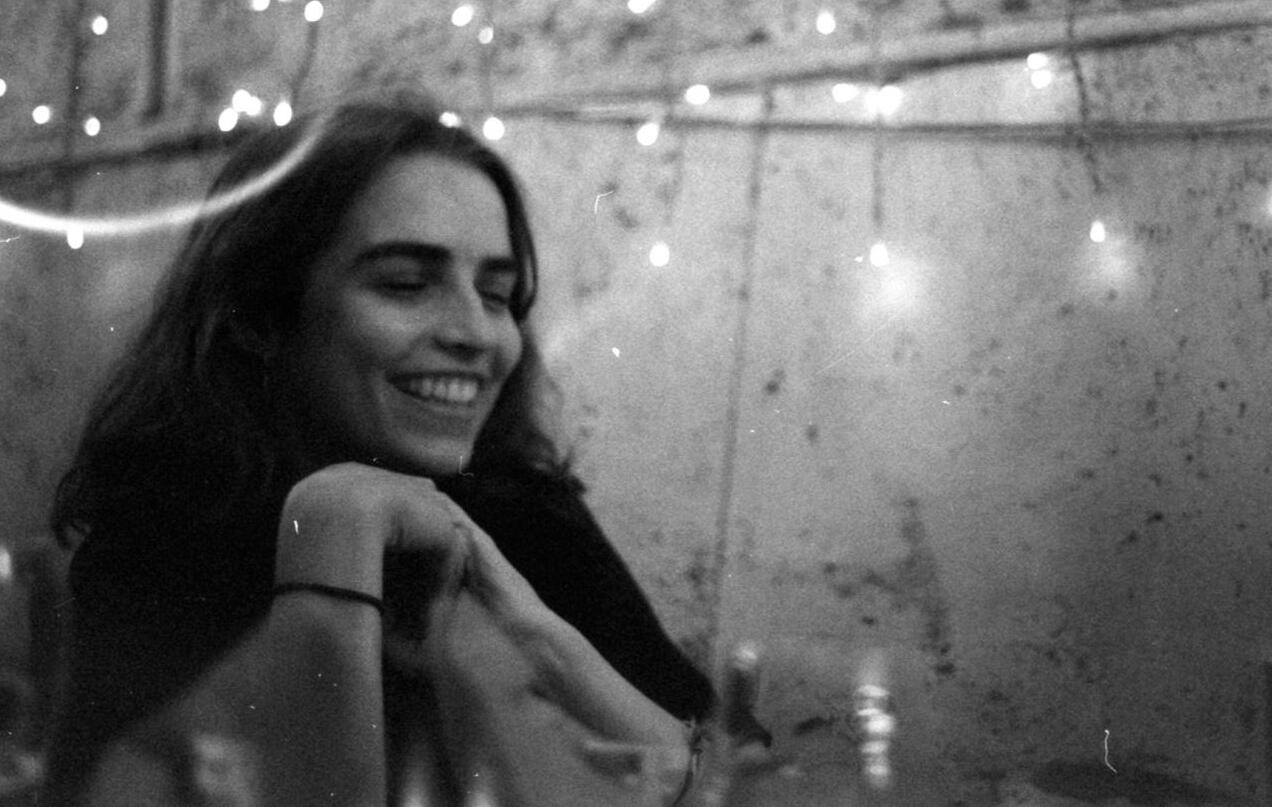 Laura Stockdale smiling for a photo in front of a painting, holding a paintbrush.